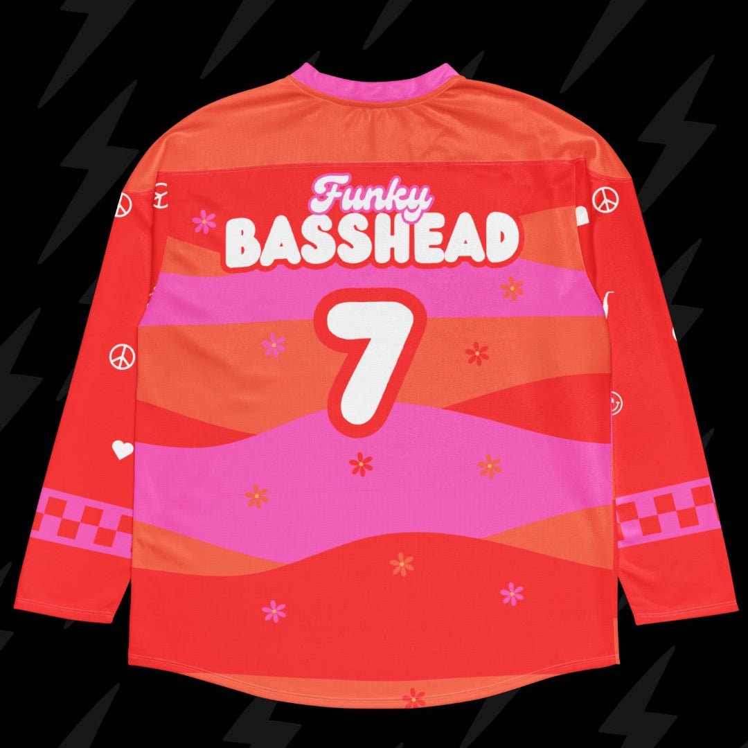A long-sleeve red and pink graphic jersey shown from the back, featuring the text 'Funky BASSHEAD' and the number '7' in white, with pink peace signs and star motifs, set against a black background with lightning bolts.