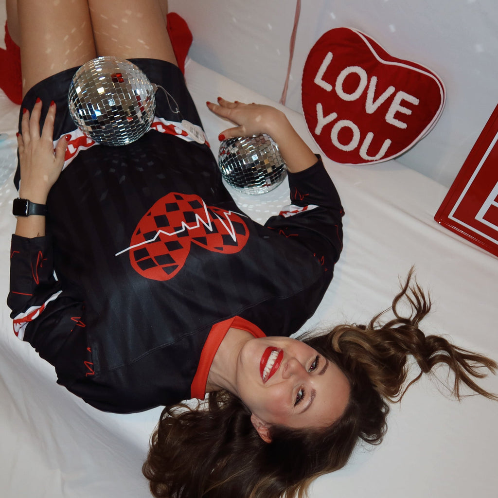 Model is wearing a red and black dubstep rave hockey jersey in a size L for the Sweet Bass Valentine's Collection. 
