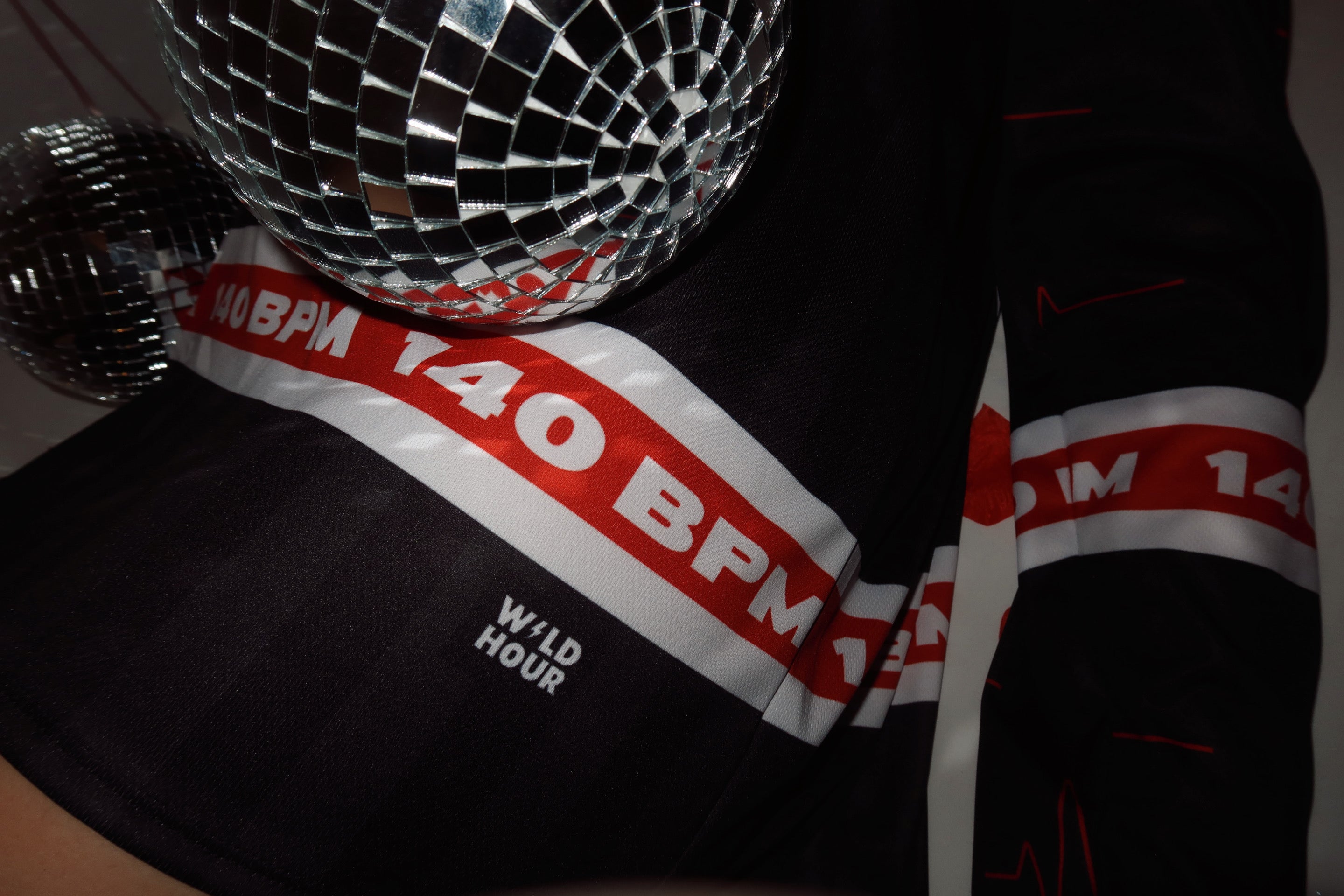 Close-up of dubstep rave 140 BPM hockey jersey with a disco ball and logo.