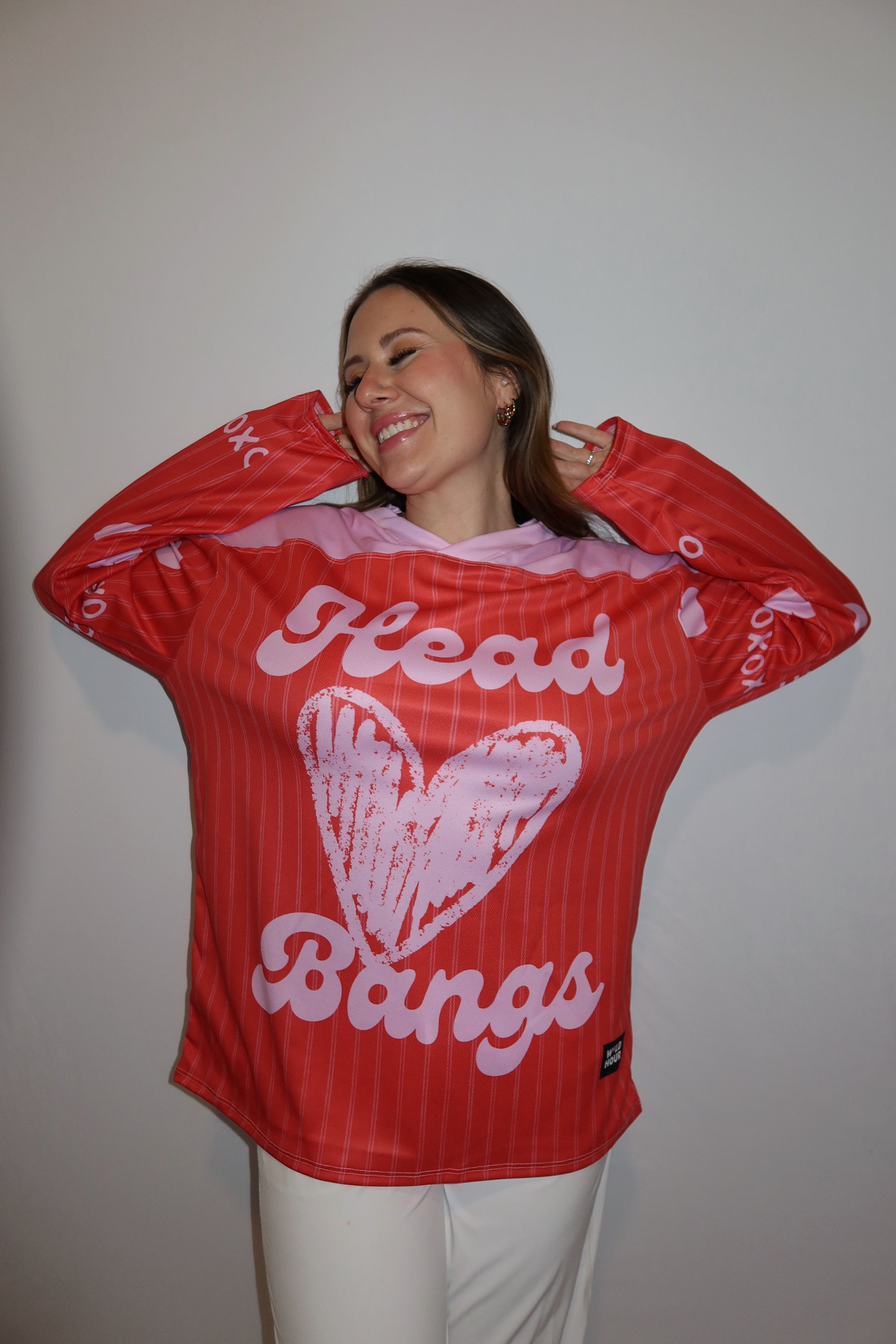 Person wearing red and pink head banger hockey jersey smiling.