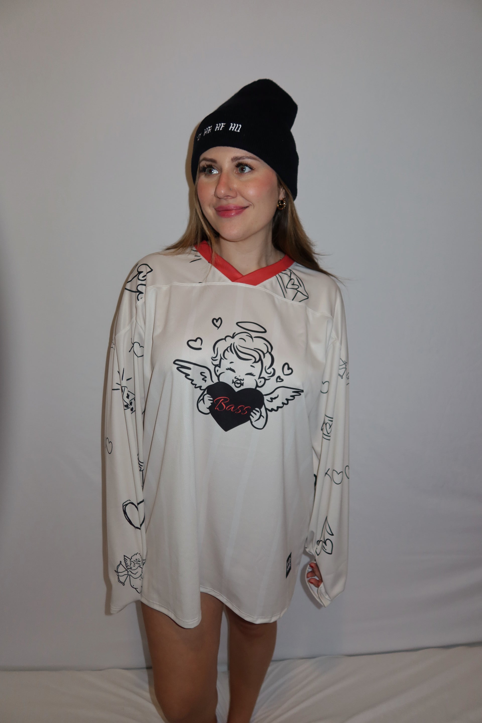 Person wearing rave hockey jersey that is cream, red, and black that has an angel on the front and says Bass.